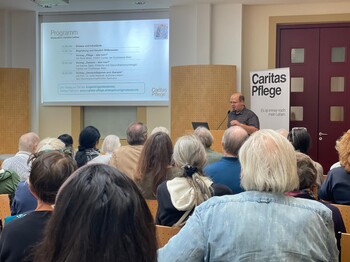 Menschen sitzen auf Stühlen und lauschen einem Vortrag Caritas Infotag für Angehörige