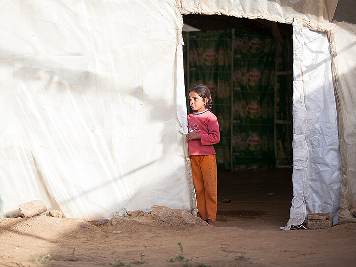 Mädchen in Flüchtlingslager vor Zelt