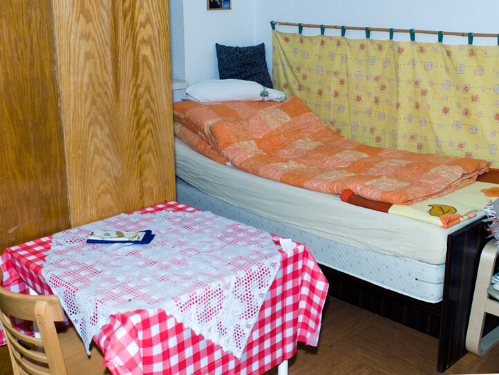 Ein Zimmer mit Bett, Tisch und Kasten